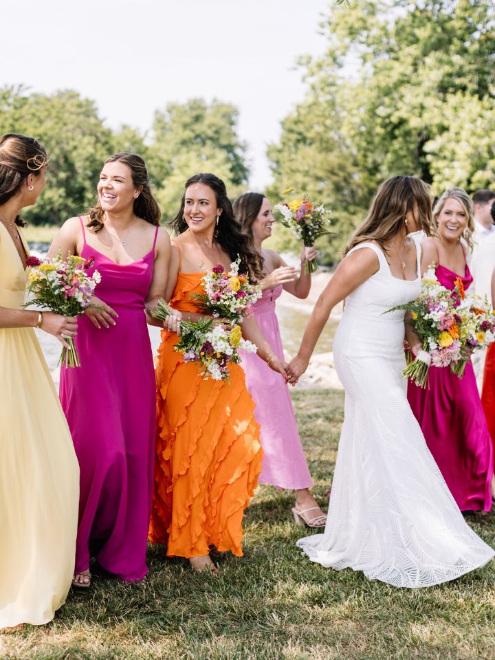 Bride and bridesmaids mingle on the lawn in bright citrus wedding colors.