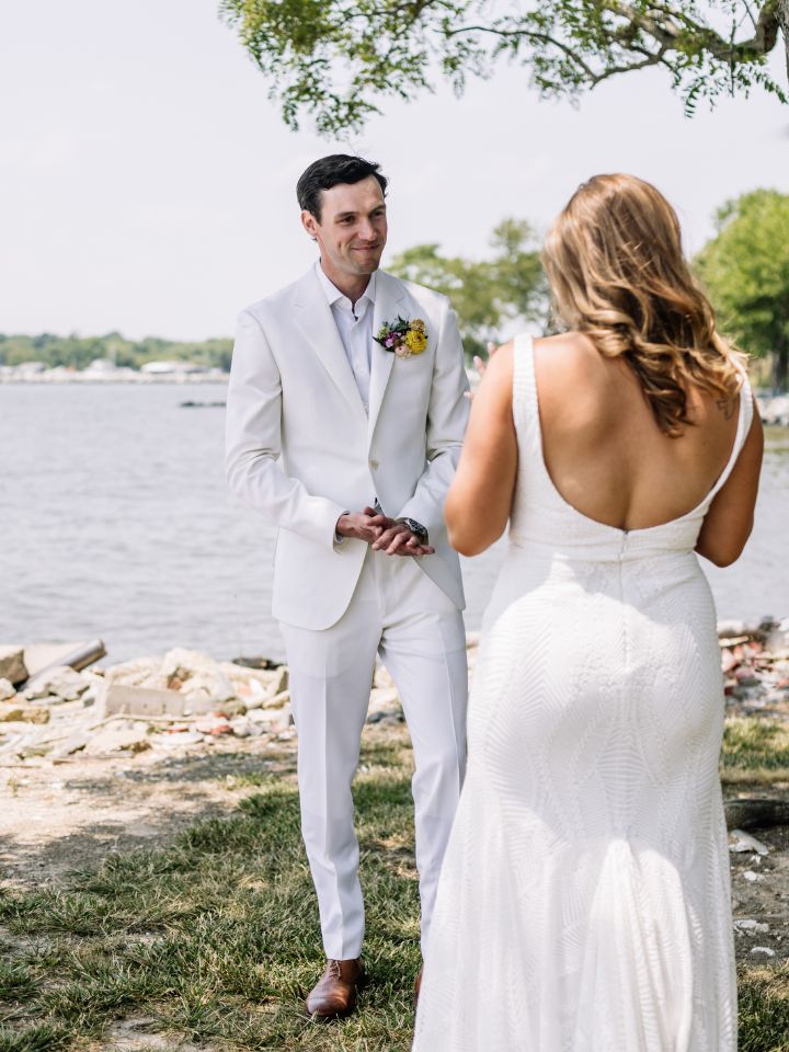 Bride surprises groom for their first look on a beach.