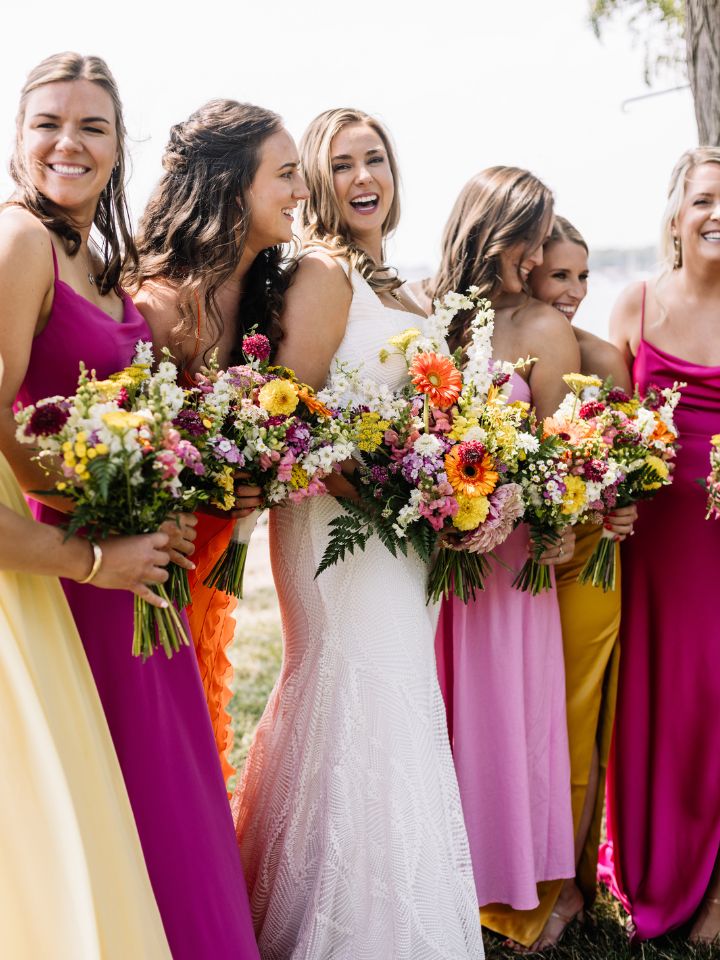 Bride smiles with her bridesmaids in bright summer colors.