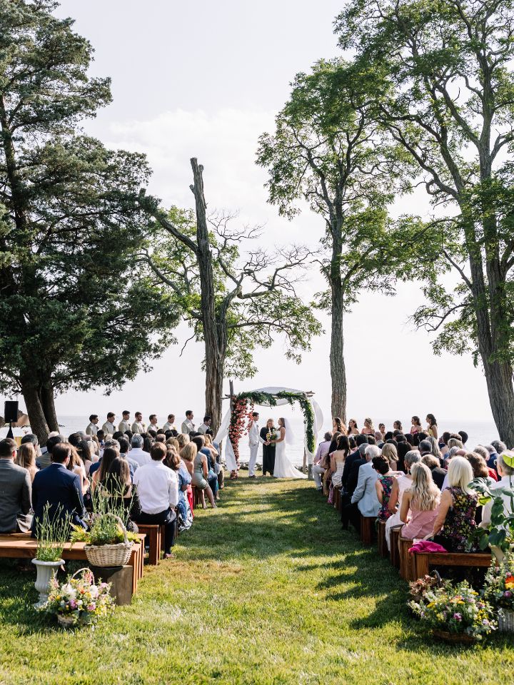 Outdoor wedding ceremony with floral aisle entrance and chuppah.