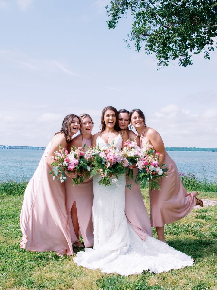 Bride and her bridesmaids in pink smile at the camera.