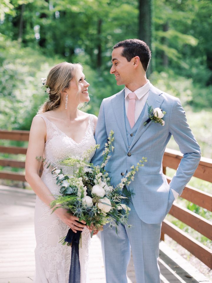 Bride and groom smile at each other with their peony wedding flowers.