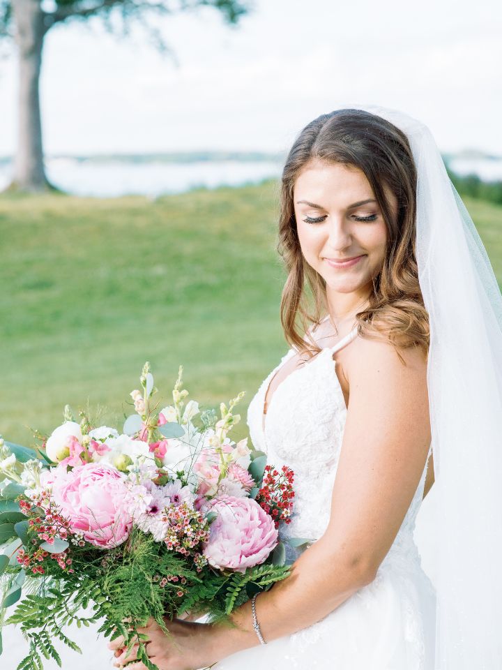 Bride looks down at her peony wedding bouquet.