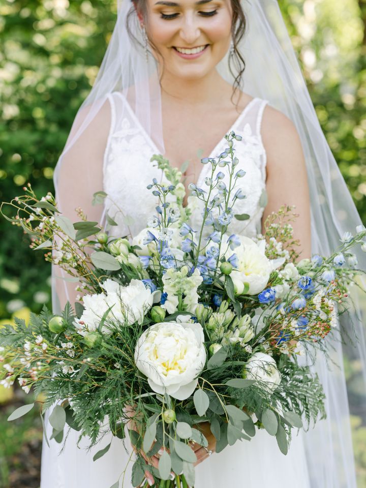 Bride smiles at her bouquet with white peonies.