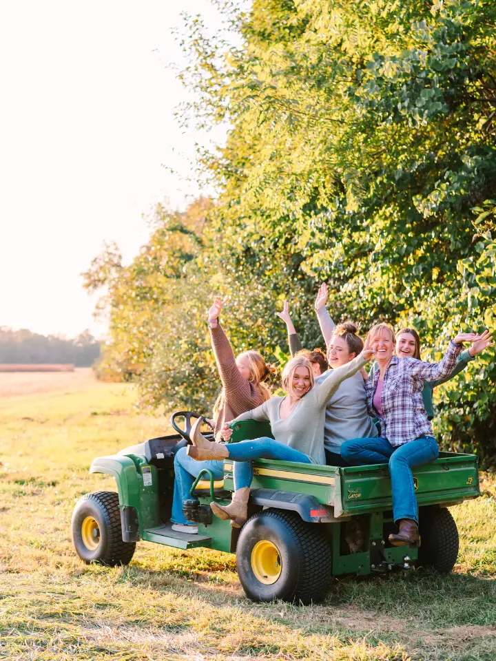 The team at Wildly Native Flower Farm sitting on a tractor and waving