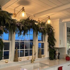 Large evergreen garland hangs over a wide kitchen window.