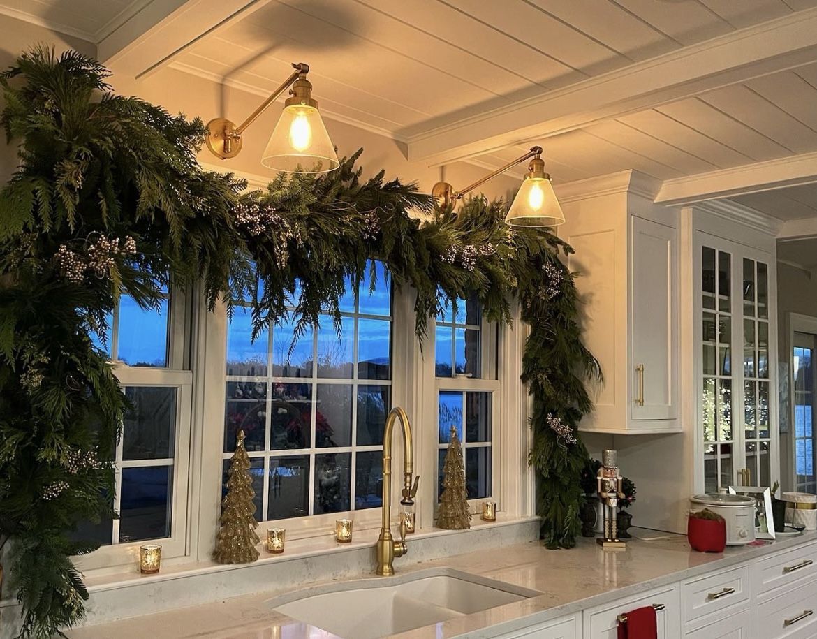 Large evergreen garland hangs over a wide kitchen window.