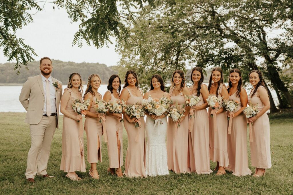 Bride surrounded by bridesmaids in peach colored dresses 