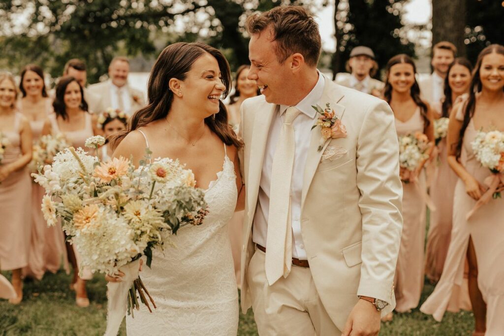 Bride and Groom smile surrounded by bridal party