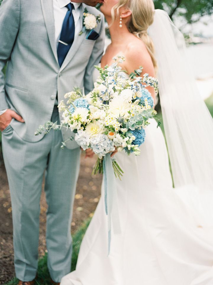 Groom in grey suit and bride holding large bouquet 