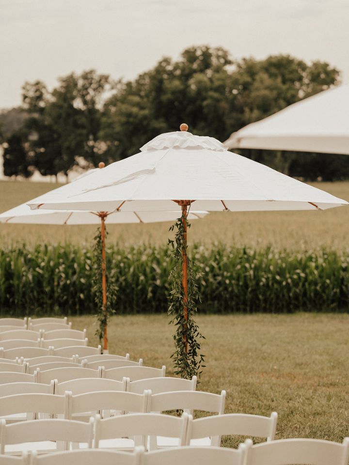 White umbrellas next to white chairs at wedding