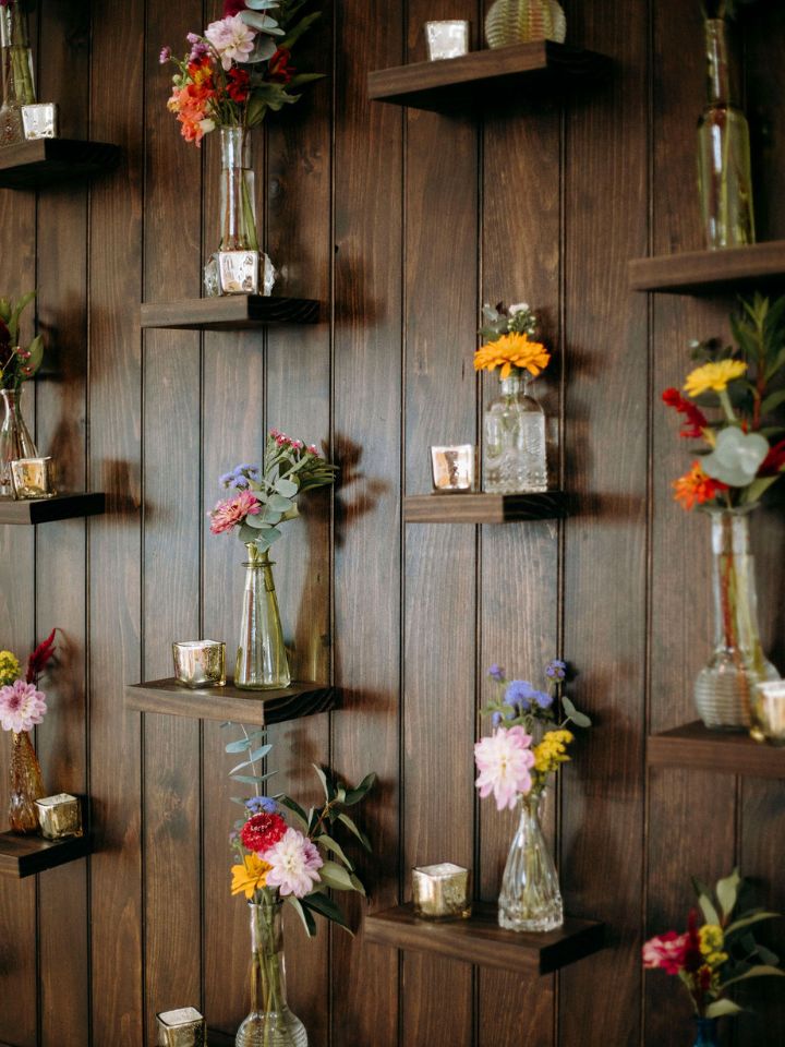 Bud vases and funky retro square votive candles arranged on shelves on a dark wood wall