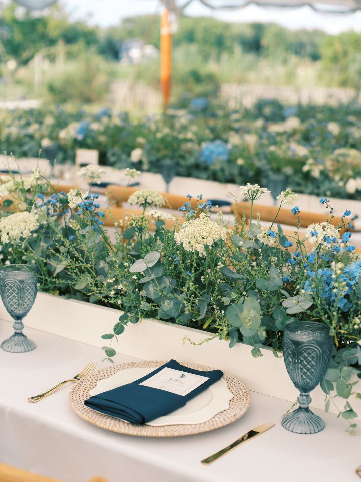 Place setting at wedding table with long planter box centerpiece filled with greenery