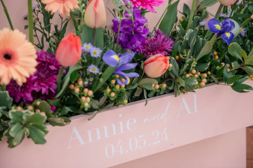 Pink flower box filled with bright colored flowers for wedding welcome sign