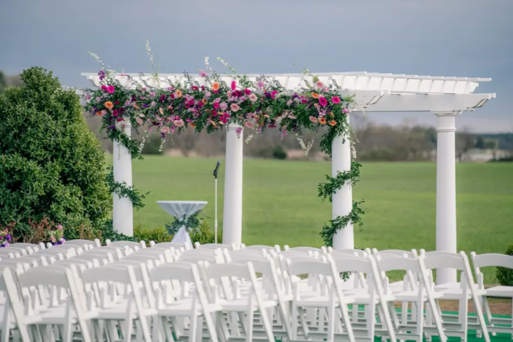 Green garlands wrapped around the columns and colorful wildflower garland draped across the top of an arch at the wedding pergola at Kent Island Resort