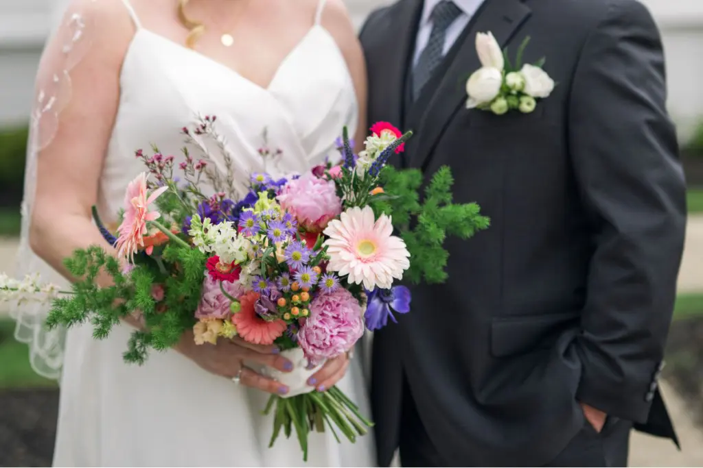 Close up of bride holding wedding bouquet and groom wearing a pocket square boutonniere