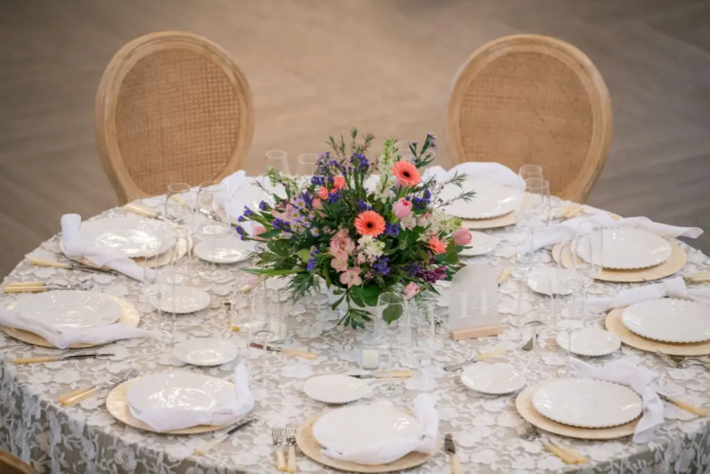 Traditional flower centerpiece in white compote for wedding guest tables