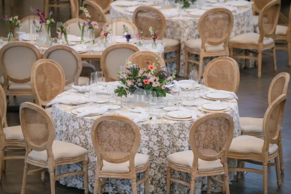 Round wedding table tablescape with lace linens and traditional compote flower centerpiece