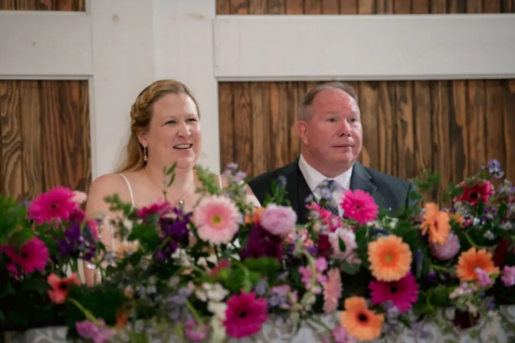 Bride and groom sit at sweetheart table with repurposed flowers from oasis garland