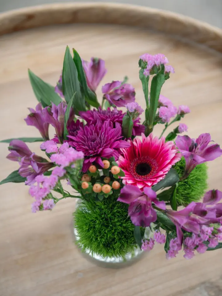 Vase filled with purple and pink flowers for cocktail hour