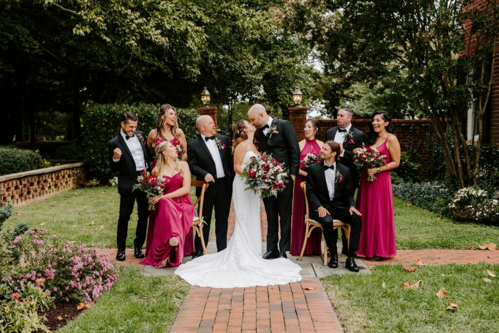 Bride and Groom pose with their wedding party in an outdoor garden.