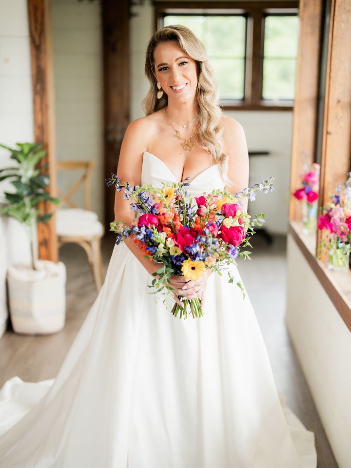 Bride holds her vibrant colorful spring wedding bouquet at the Kent Island Resort Farmstead.