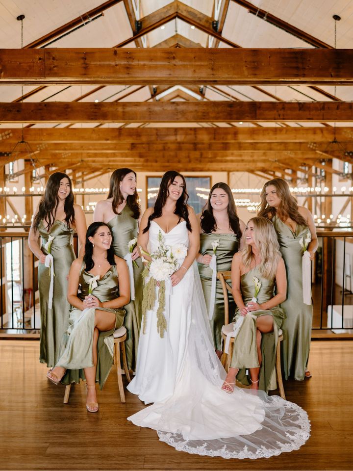 Bride and her bridesmaids get ready and pose with white and green floral bouquets.