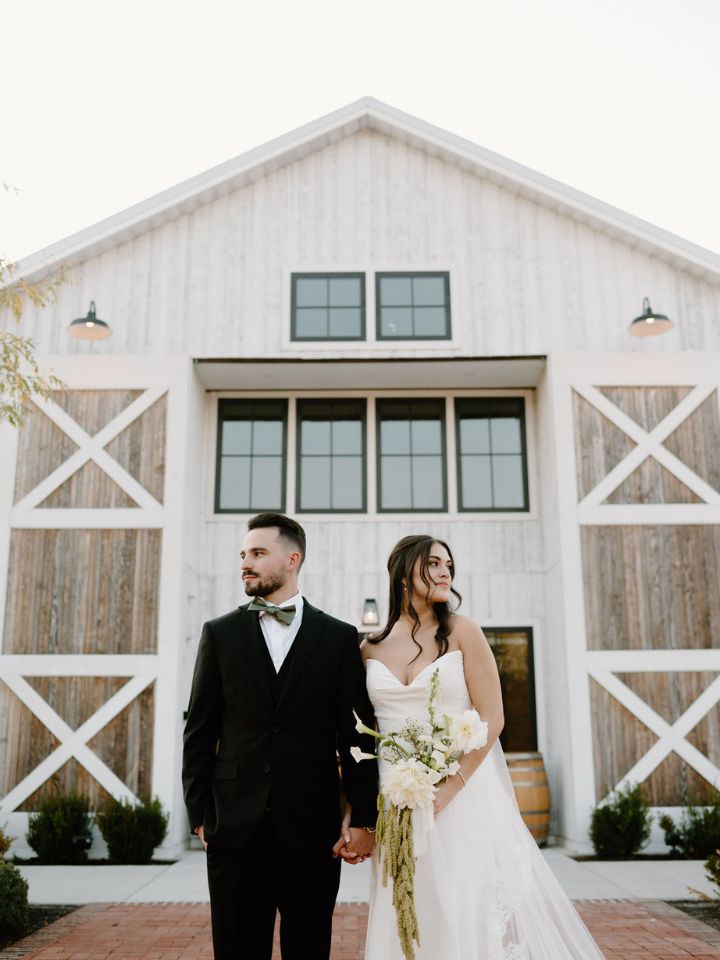 Bride and Groom pose in front of the Kent Island Resort Farmstead.