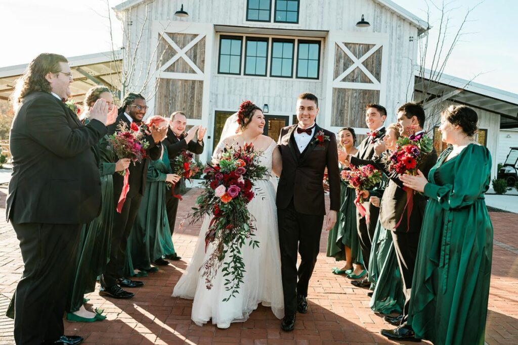 Bride and Groom walk down aisle of their wedding party, smiling and holding bridal bouquet.