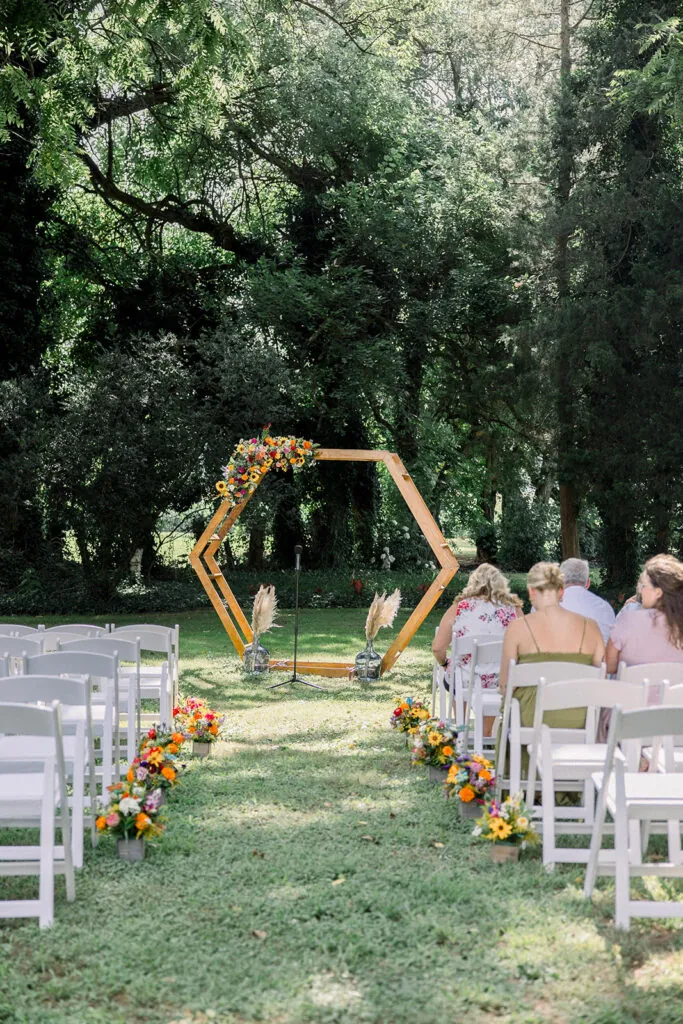 View of an outdoor wedding ceremony at Worsell Manor with aisle flowers and an arch.