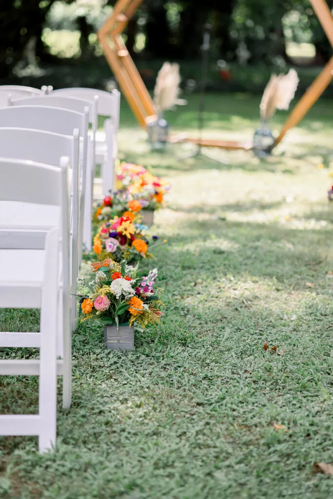 Small wood boxes full of flowers line the aisle at an August wedding.