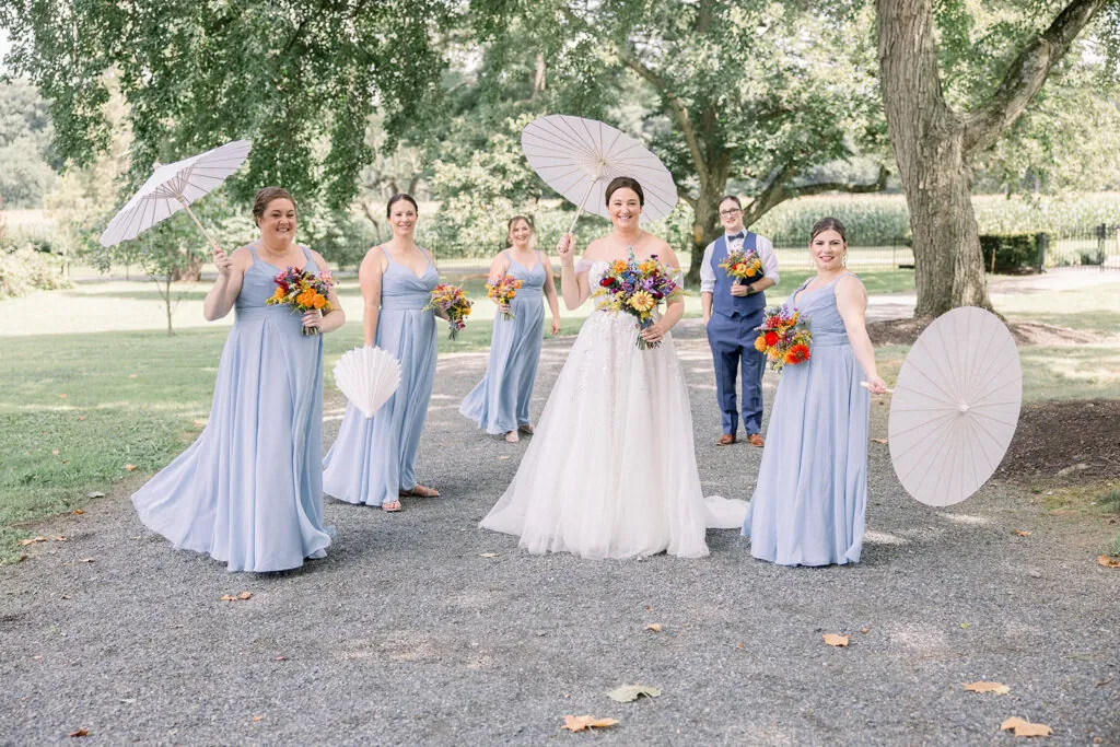The bridal party holds their LEGO Flowers bouquets and white parasols.